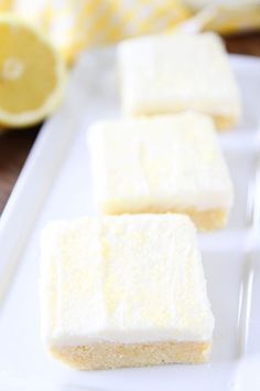 three squares of cake sitting on top of a white plate next to a lemon slice