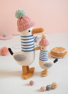 two crocheted birds standing next to each other on top of a white table