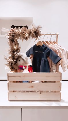 a wooden crate filled with clothes on top of a white counter next to a teddy bear