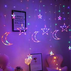 some stars and moon lights hanging from the ceiling in a purple room with balloons on the floor