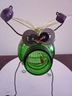 a green glass vase sitting on top of a white plate next to a black cord