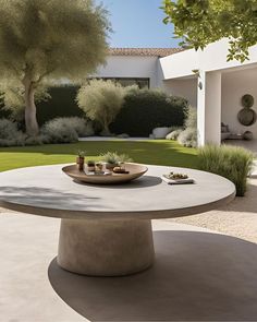 an outdoor table with plates on it in the middle of a courtyard area, surrounded by trees and bushes