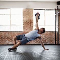 a man is doing push ups on a mat in an empty room with brick walls