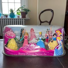 there are many princess figurines in the plastic box on the table next to the chair