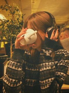 a woman wearing headphones and holding a cup