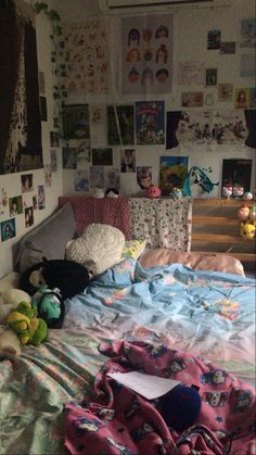 an unmade bed with lots of pictures on the wall above it and stuffed animals