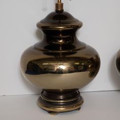 two shiny gold vases sitting next to each other on a white counter top, one is turned upside down