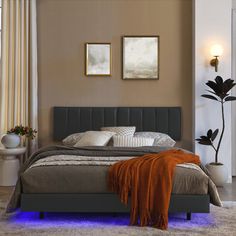 a bedroom with a large bed and two pictures on the wall above it, along with an orange throw blanket