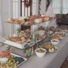 an assortment of food is displayed on a long table in front of a christmas tree