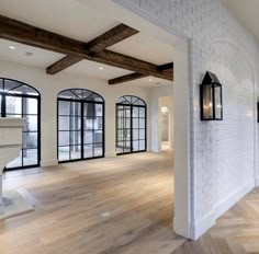 an empty living room with wood floors and white brick walls, along with large windows