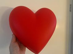 a heart shaped balloon being held up against a wall