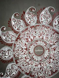 an intricately designed piece of art on the ground with red and white designs around it