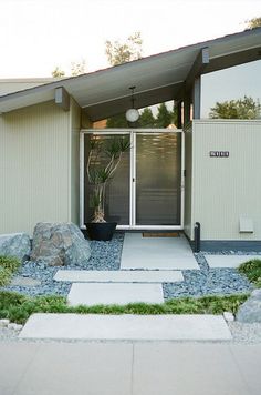 an entrance to a home with rocks and grass