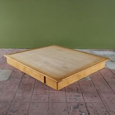 a wooden table sitting on top of a brick floor next to a green wall and white tiled floor