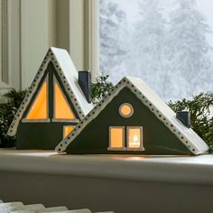 two small houses are lit up in the window sill