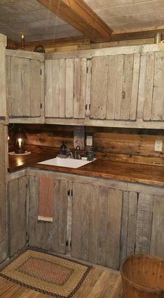 an old fashioned kitchen with wooden cabinets and wood flooring on the walls, along with a white sink