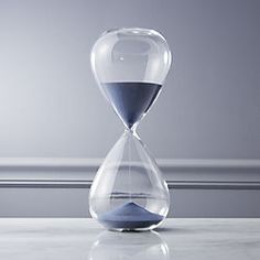 an hourglass with blue sand sitting on a white countertop next to a gray wall