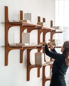 a woman standing in front of a wall with bookshelves and shelves on it