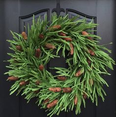 a wreath with pine cones is hanging on the front door, and it's ready to be hung