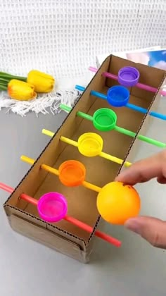 a person is playing with an assortment of colored plastic cups and straws in a cardboard box