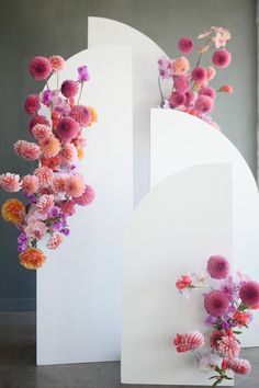 two white sculptures with pink and orange flowers hanging from them