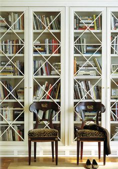 two chairs sitting in front of a bookcase with books on it and leopard print covers