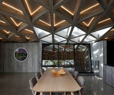 a wooden table surrounded by chairs in front of a wall with lights on it's sides