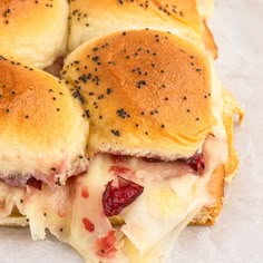 four sliders with meat and cheese on them sitting on wax paper covered in black pepper flakes