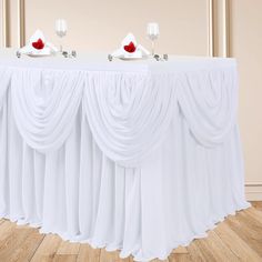 the table is set with two wine glasses on top of it and one red rose