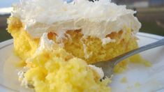 a piece of cake with white frosting and a fork on a plate next to it