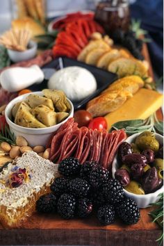 an assortment of food is displayed on a long table with bread, grapes, and other foods