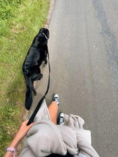 a person laying on the ground with their feet in the air and a black dog standing next to them