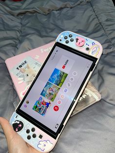 a person holding a nintendo wii game controller in front of a laptop on a bed