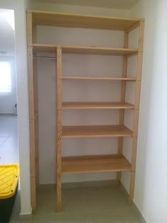 empty shelves in the corner of a room with yellow bins on the floor next to them