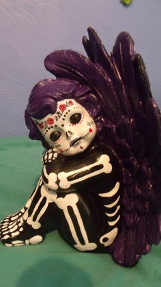 a skeleton figurine sitting on top of a green table next to a purple wall