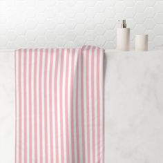 a pink and white striped towel hanging on the wall next to two rolls of toilet paper