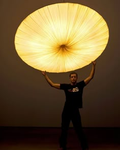 a man is holding up a large light in the air with his hands and arms