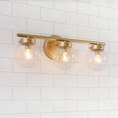 three light bathroom fixture with glass globes on white brick wall in modern home setting