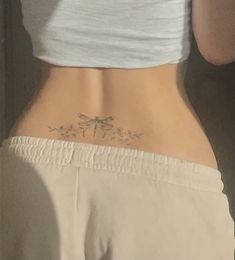 the back of a woman's stomach with a dragonfly tattoo on it