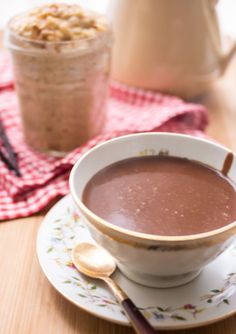 there is a cup of chocolate on the saucer with spoons next to it