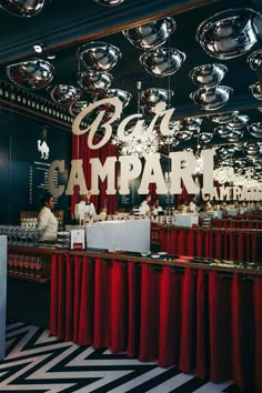 the interior of a restaurant with red curtains and black and white striped flooring, chandeliers hanging from the ceiling