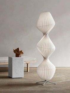 a large white vase sitting on top of a wooden floor next to a table and chair