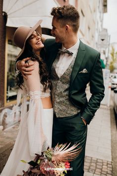 a man in a suit and tie standing next to a woman wearing a wedding dress