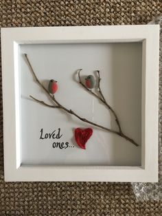 two birds sitting on branches in a frame with the words loved ones painted on it