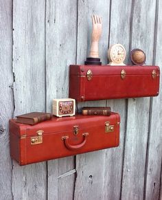 two pieces of red luggage sitting on top of a wooden wall next to each other