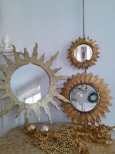 there are three mirrors on the table and one has gold sunbursts hanging from it