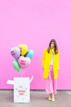 a woman standing next to a box with balloons in it