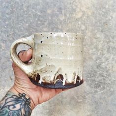 a hand holding a coffee cup with white paint on it