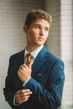 a young man in a suit and tie poses for the camera with his hands on his chest