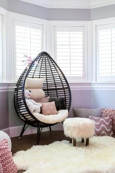 a chair and ottoman in a room with white carpeted flooring, large windows and shutters